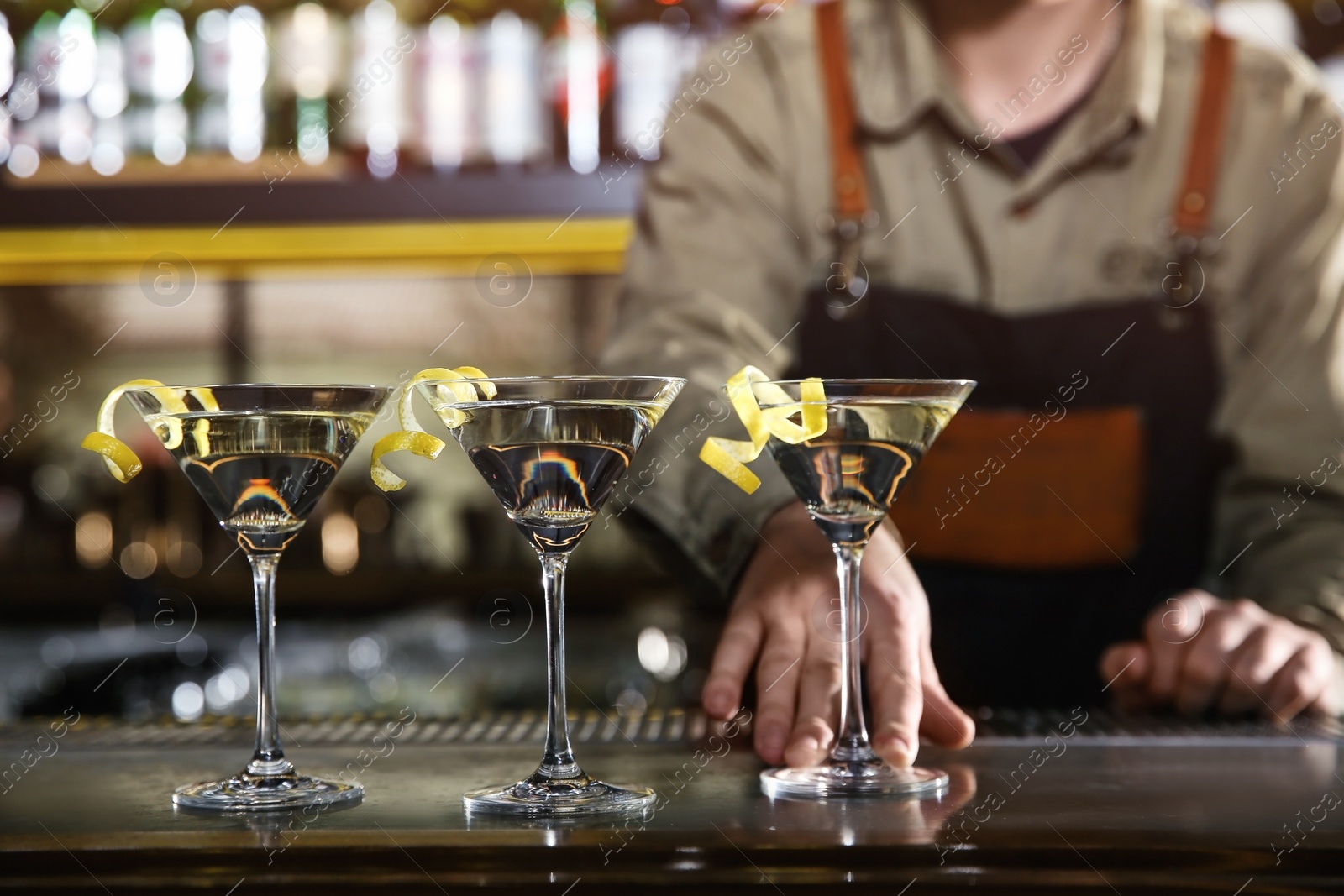 Photo of Barman serving glasses of lemon drop martini on counter, closeup. Space for text