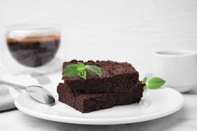 Delicious brownies with mint on white table, closeup