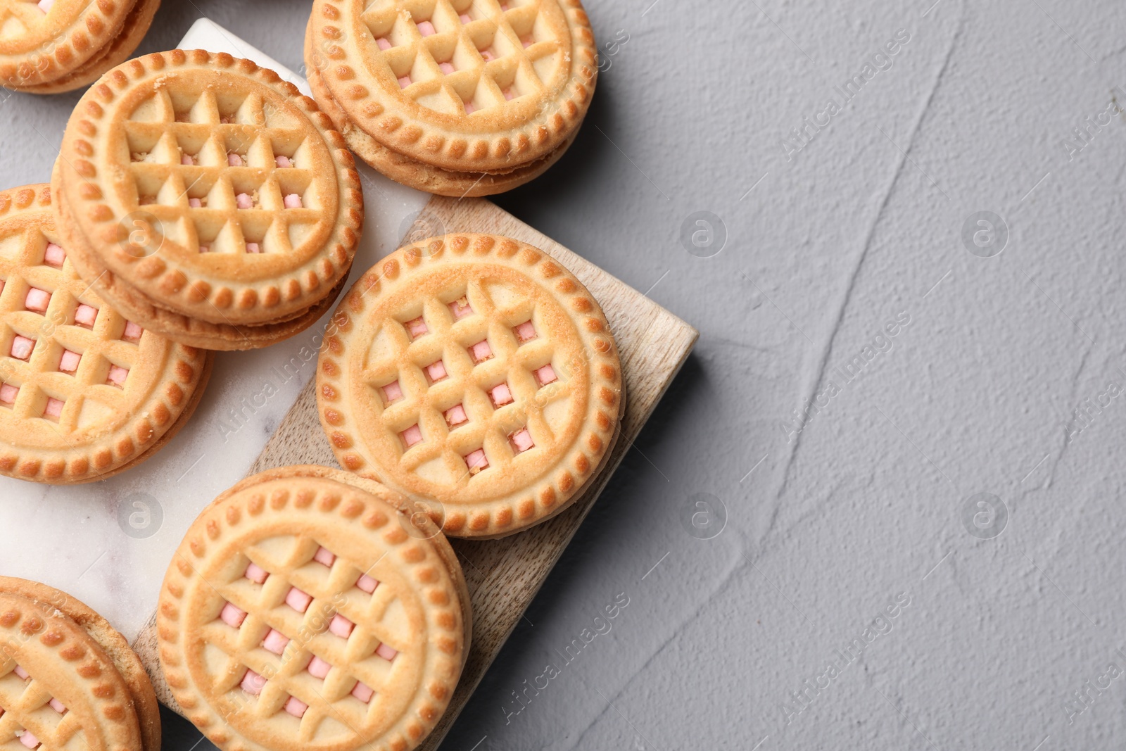 Photo of Tasty sandwich cookies with cream on light grey table, flat lay. Space for text