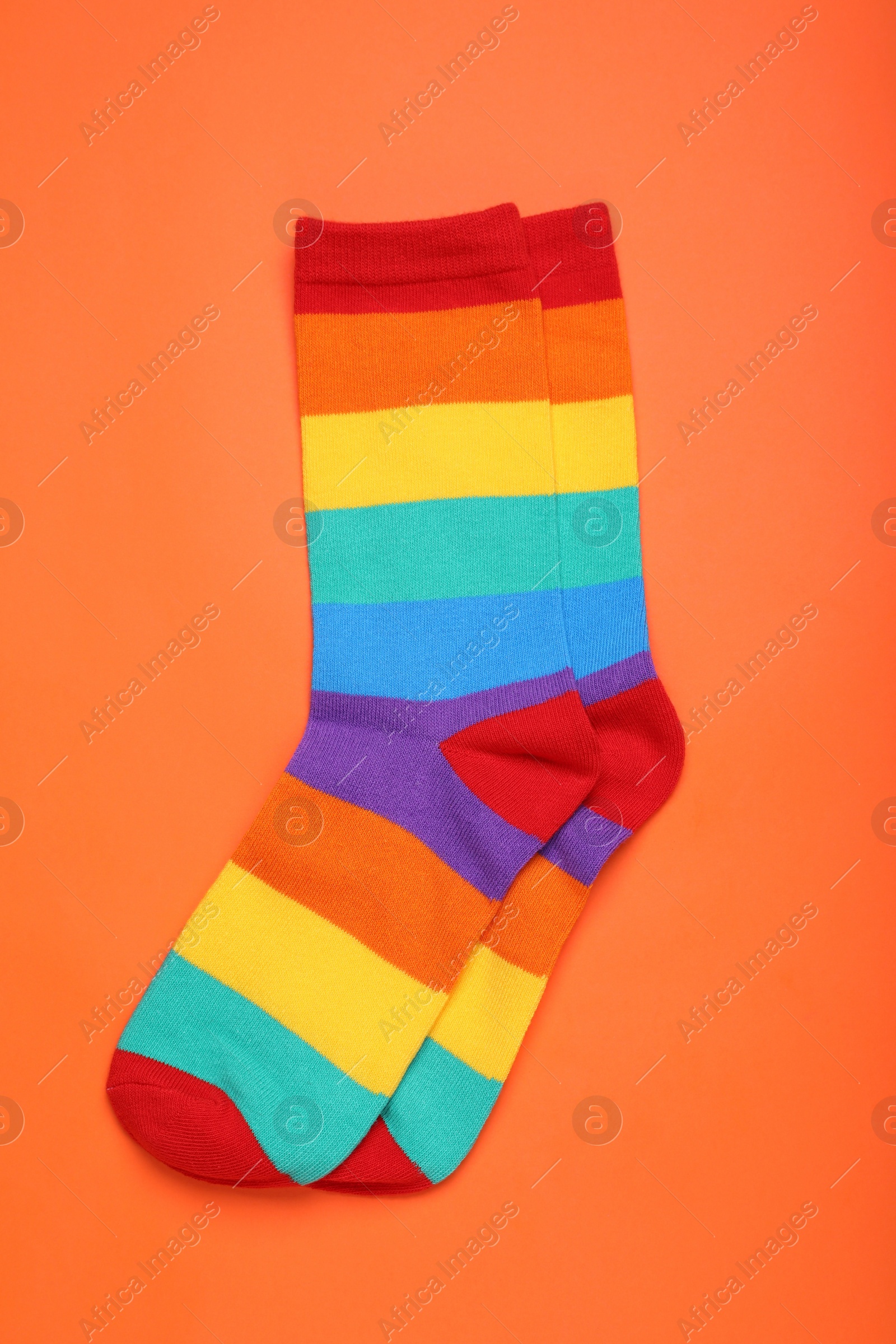 Photo of Rainbow socks on orange background, flat lay. LGBT pride