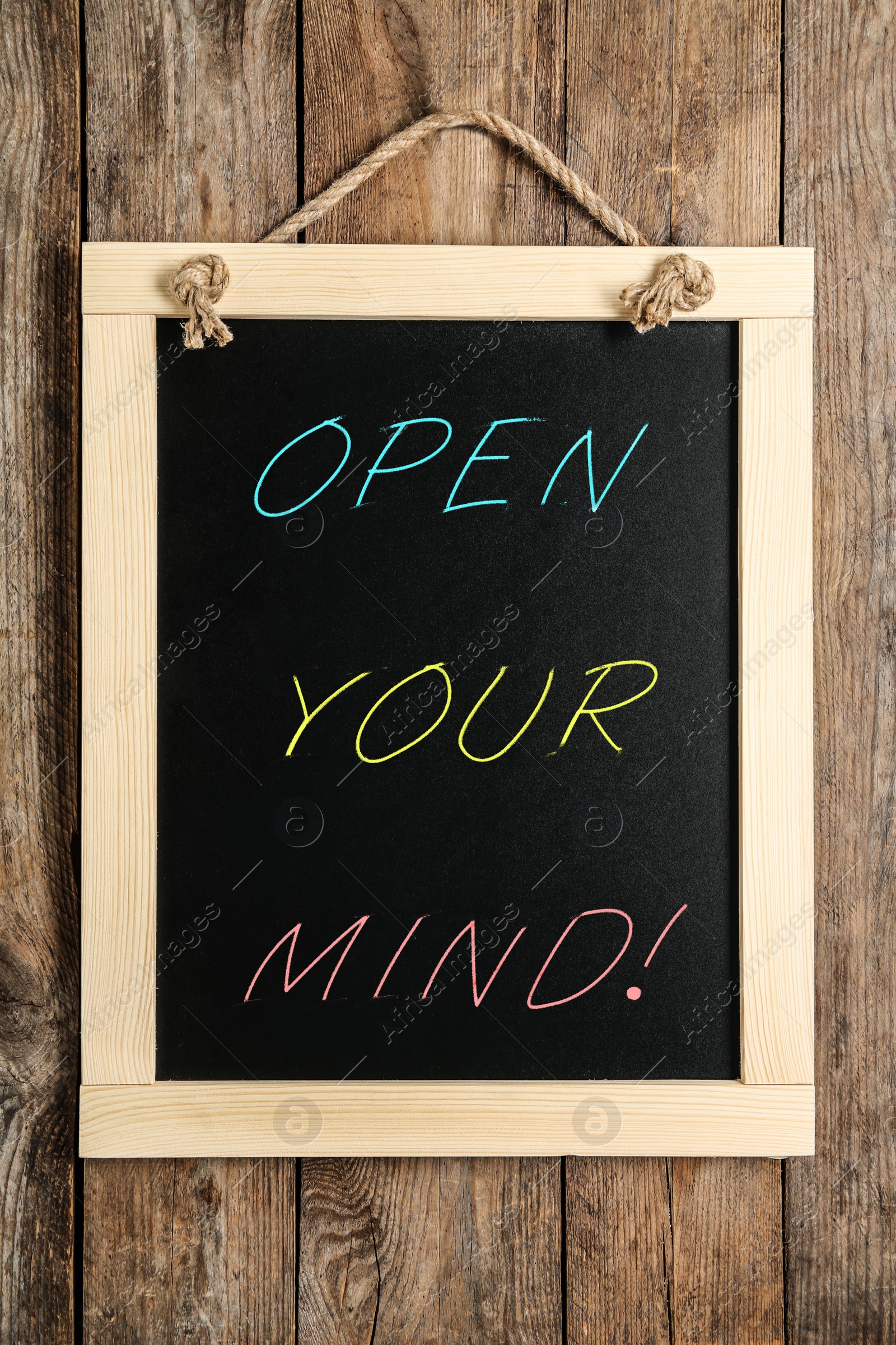Image of Small chalkboard with motivational quote Open your mind hanging on wooden wall