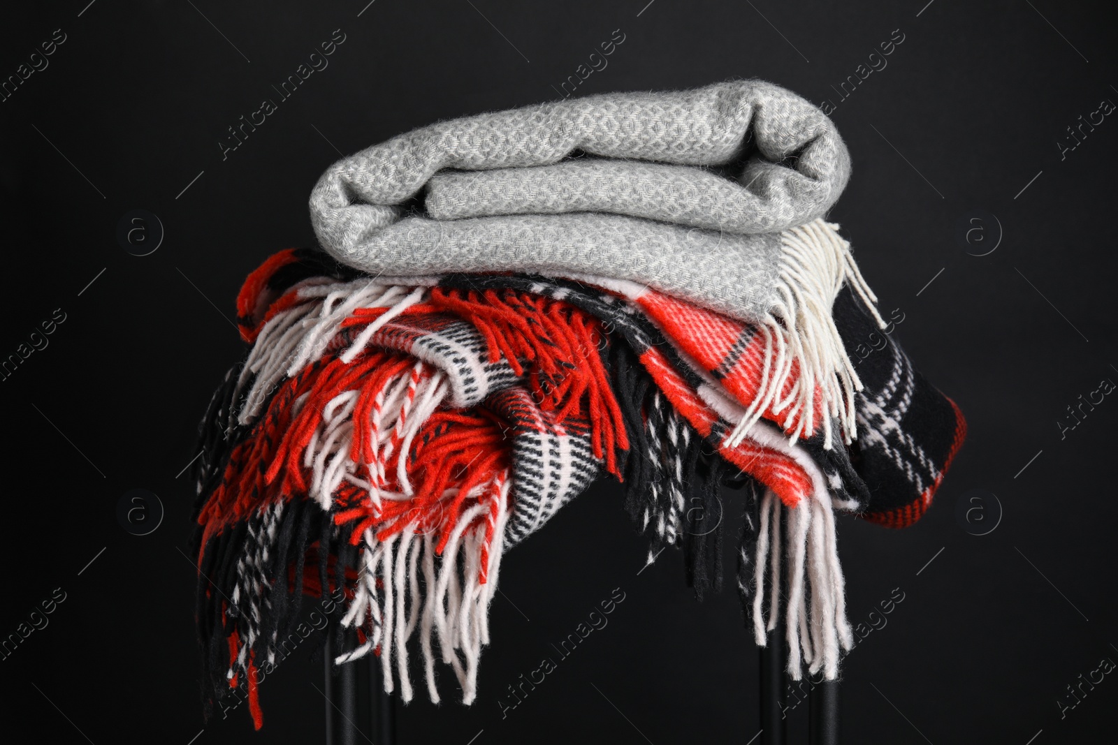 Photo of Stack of knitted plaids on black background