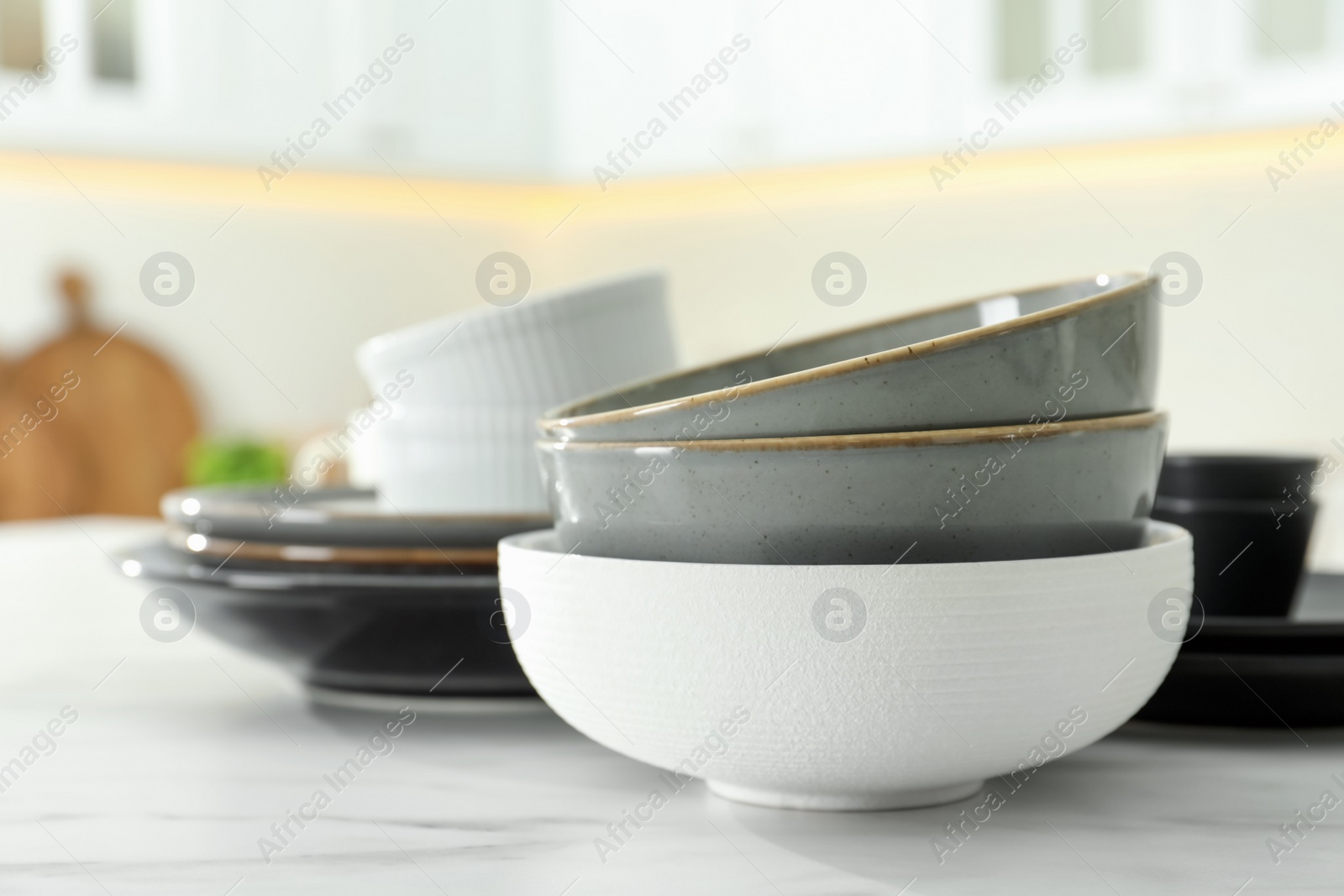 Photo of Set of ceramic tableware on white table in kitchen, closeup