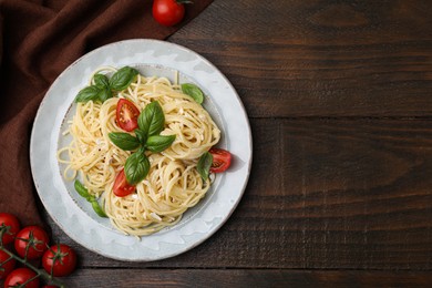Photo of Delicious pasta with brie cheese, tomatoes and basil leaves on wooden table, flat lay. Space for text