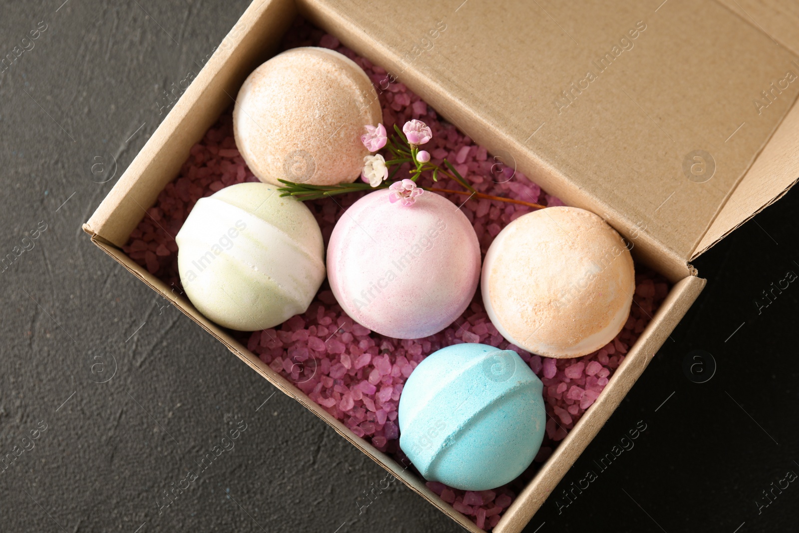 Photo of Carton box with bath bombs on black background, top view