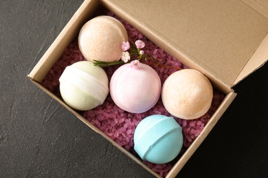 Carton box with bath bombs on black background, top view