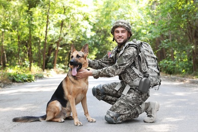 Photo of Man in military uniform with German shepherd dog outdoors