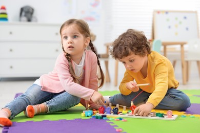 Cute little children playing with math game Fishing for Numbers on puzzle mat in kindergarten