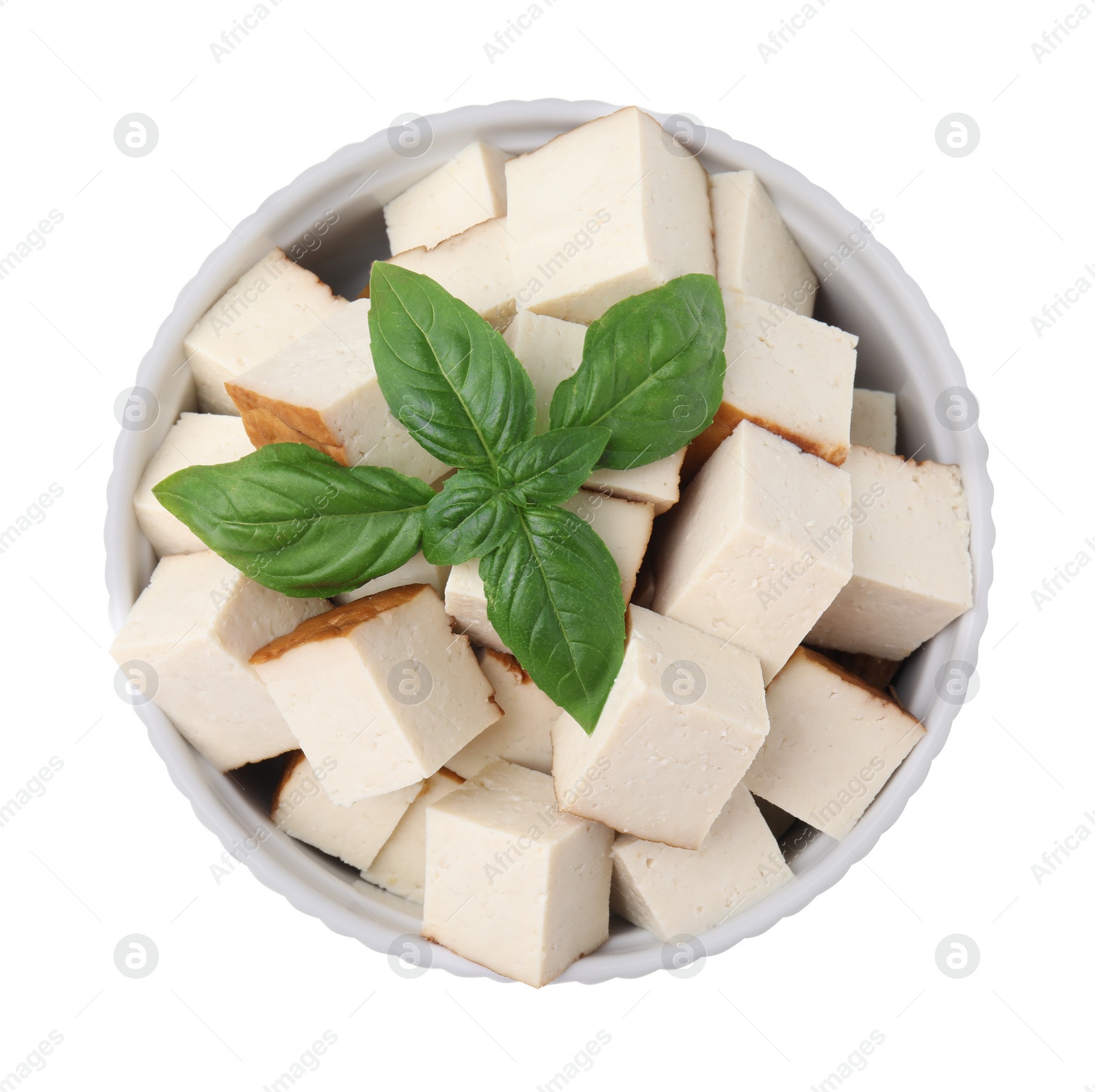 Photo of Bowl of delicious smoked tofu cubes with basil isolated on white, top view