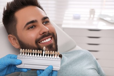 Photo of Dentist checking young man's teeth color in clinic