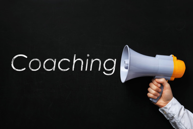 Image of Adult learning. Man holding megaphone near chalkboard with word Coaching, closeup