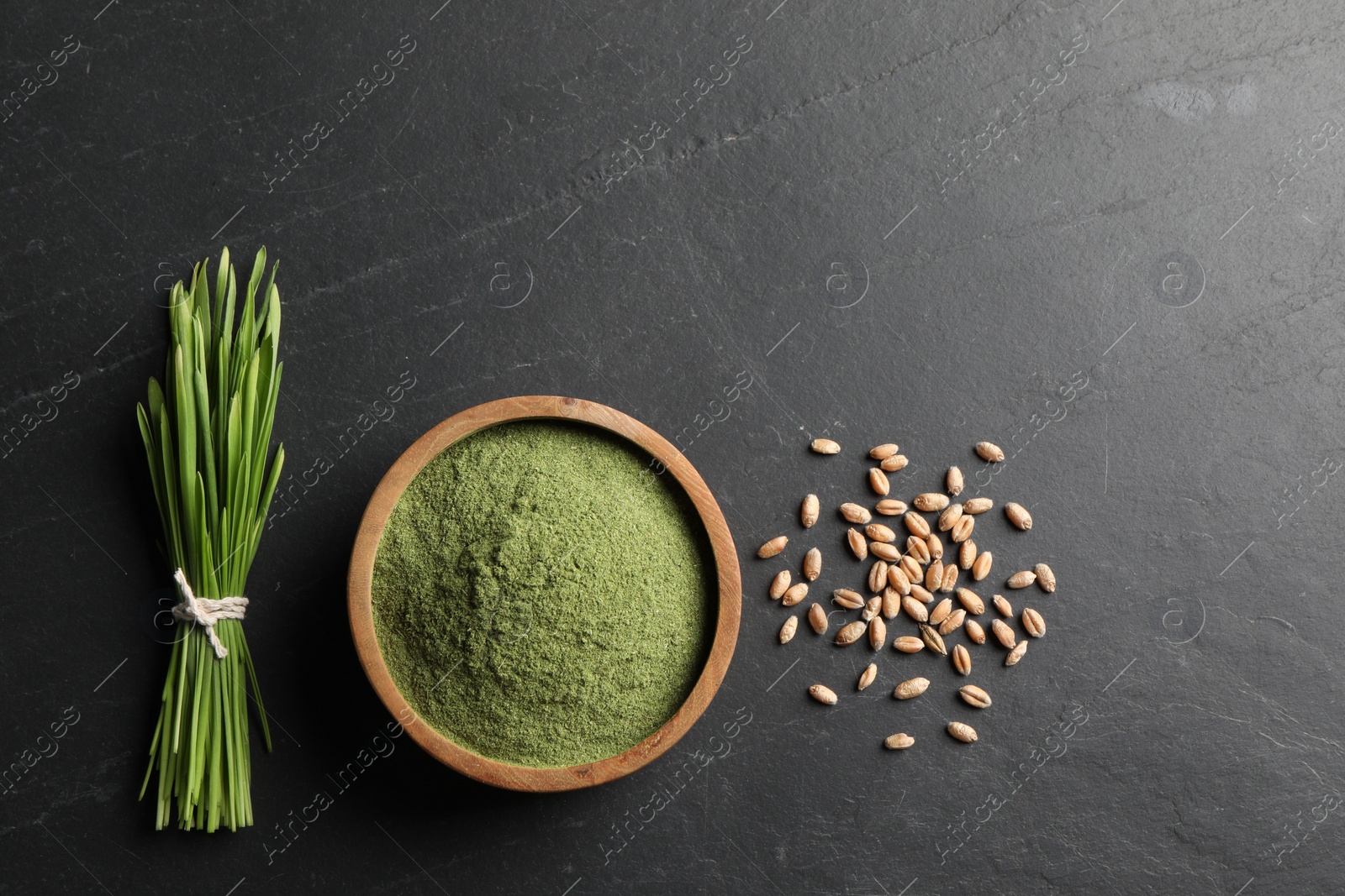 Photo of Wheat grass powder in bowl, seeds and fresh sprouts on grey textured table, flat lay