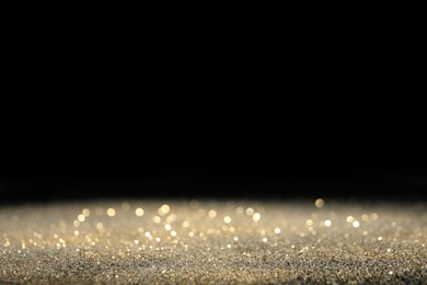 Photo of Shiny golden glitter on black background, space for text. Bokeh effect