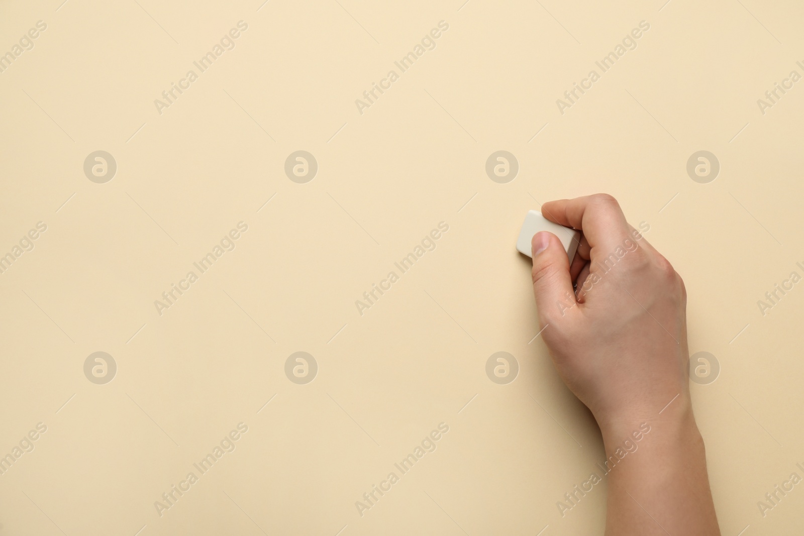 Photo of Man erasing something on beige background, closeup. Space for text