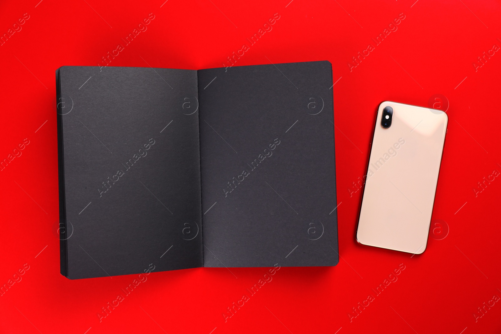 Photo of Open black notebook with smartphone on colorful background, flat lay