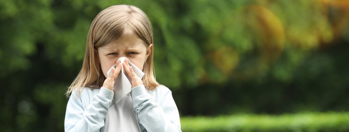 Little girl suffering from seasonal spring allergy outdoors. Banner design with space for text