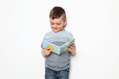 Cute little boy reading book on white background