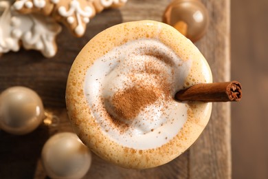 Photo of Tasty eggnog with cinnamon, cookies and Christmas baubles on wooden table, flat lay