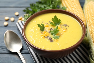 Photo of Delicious creamy corn soup served on blue wooden table