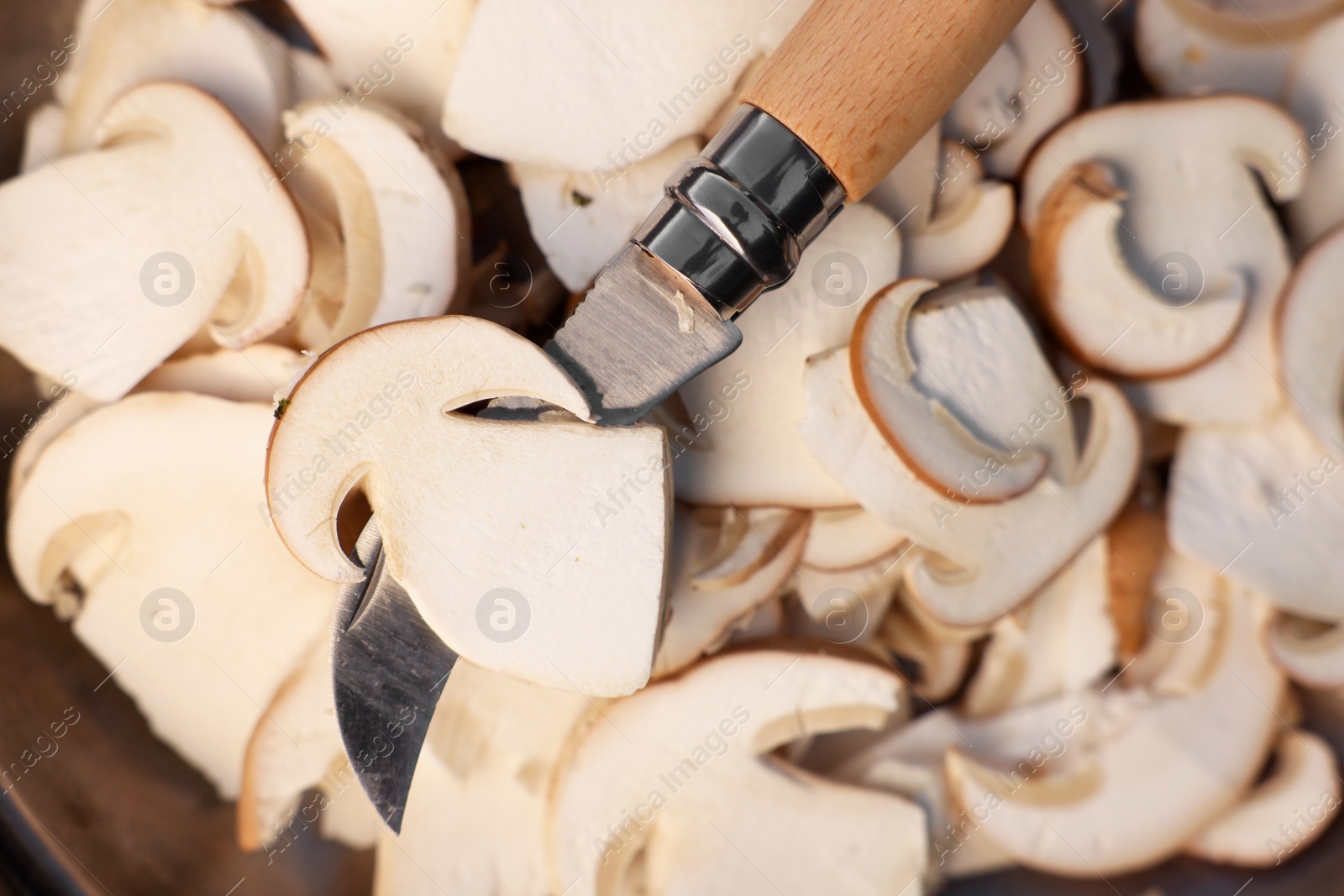 Photo of Pile of cut mushrooms with knife as background, closeup