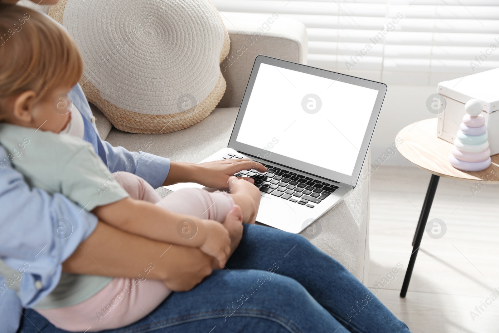 Photo of Mother and daughter with laptop on sofa at home. Pediatrician online consultation