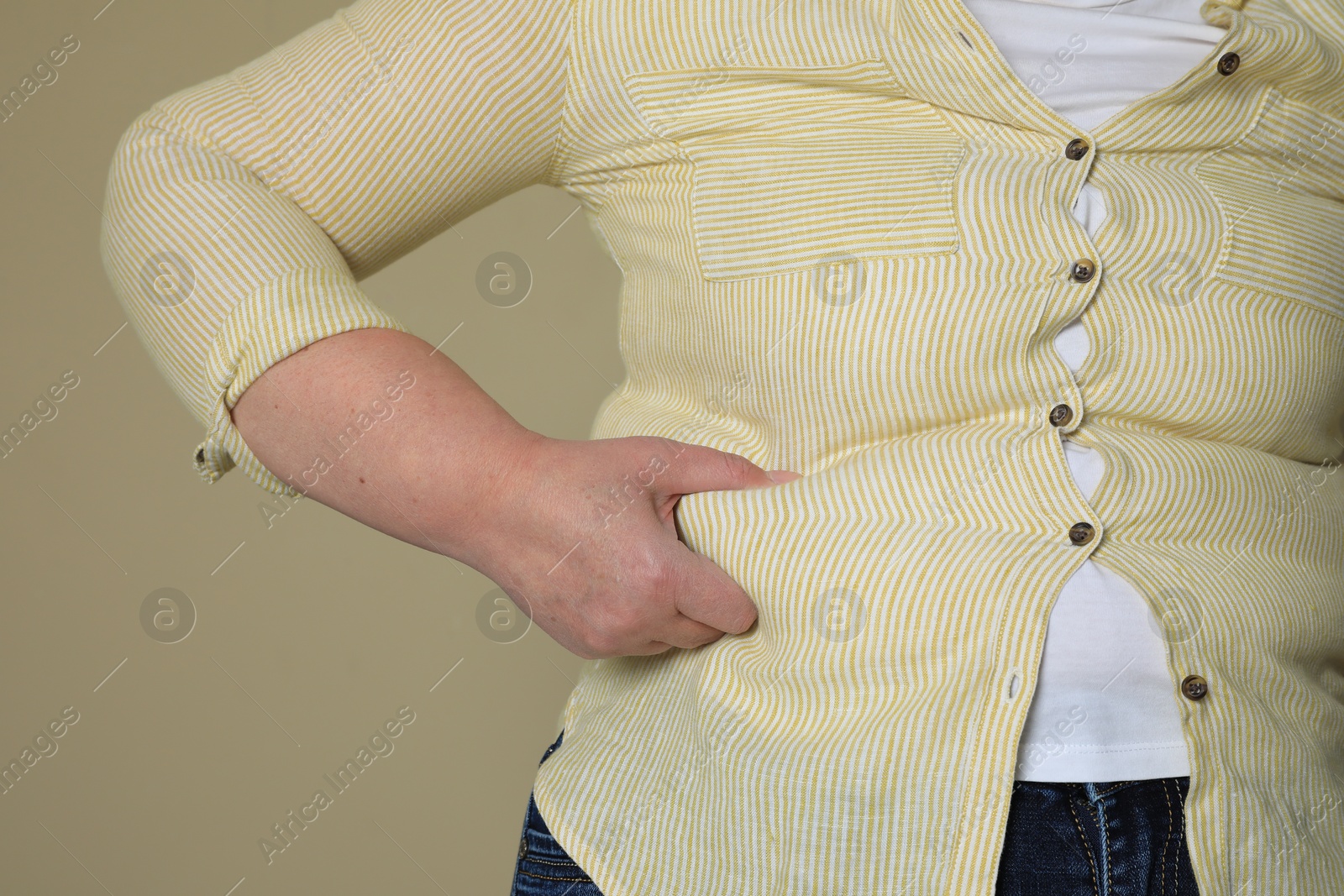 Photo of Overweight woman in tight shirt on beige background, closeup