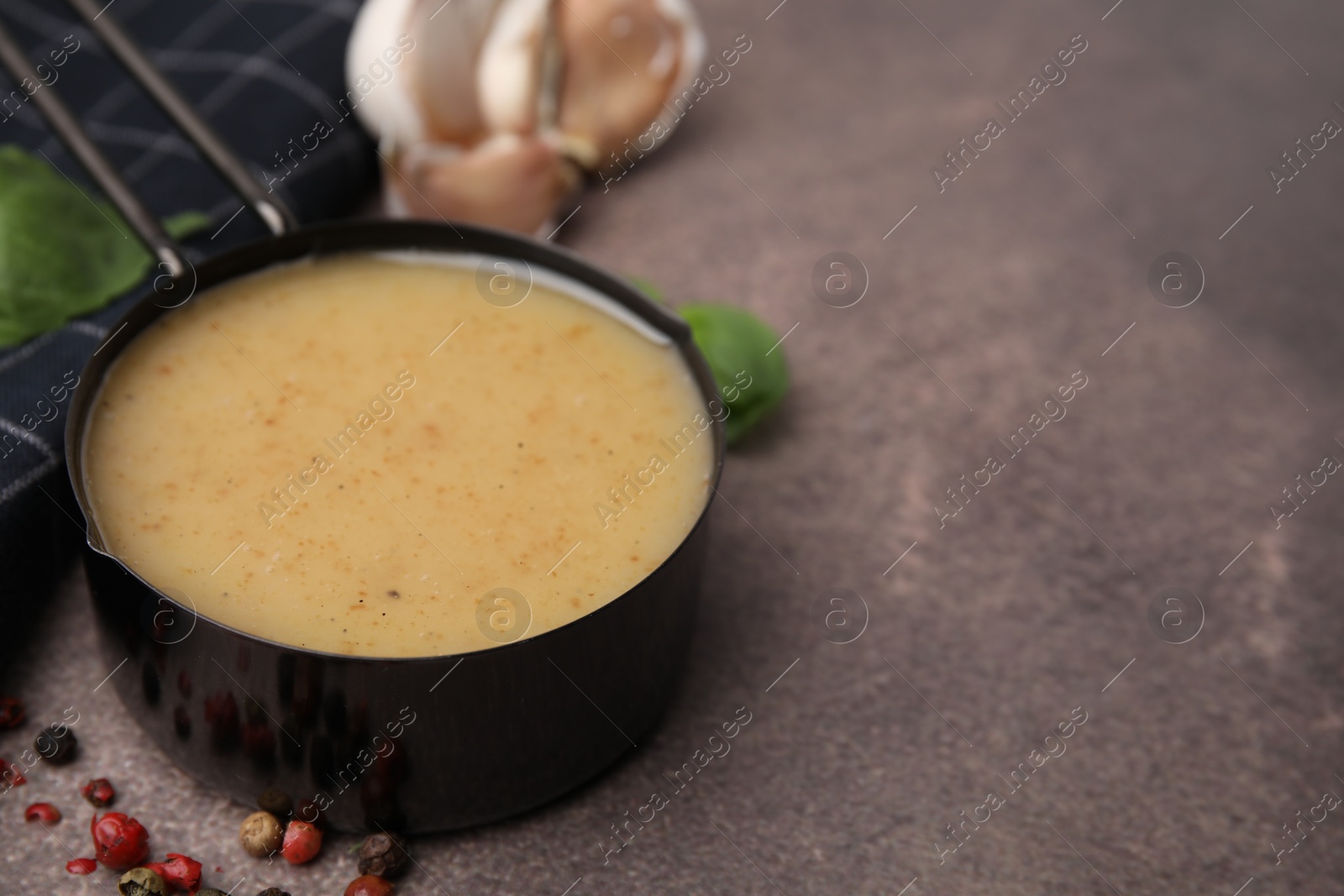 Photo of Delicious turkey gravy, peppercorns and garlic on brown textured table, closeup. Space for text