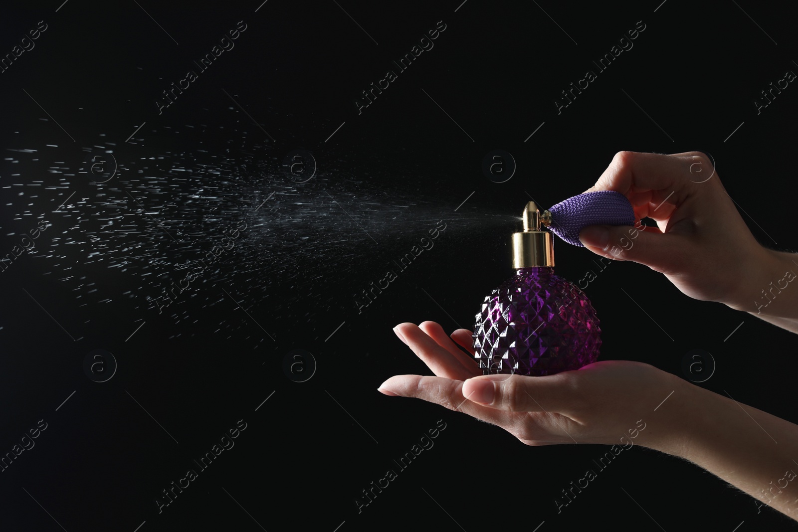 Photo of Woman holding bottle of luxury perfume on black background, closeup. Space for text