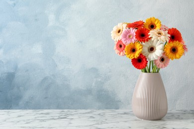 Photo of Bouquet of beautiful colorful gerbera flowers in vase on white marble table against light blue background. Space for text