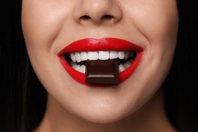 Photo of Young woman with red lips eating chocolate, closeup