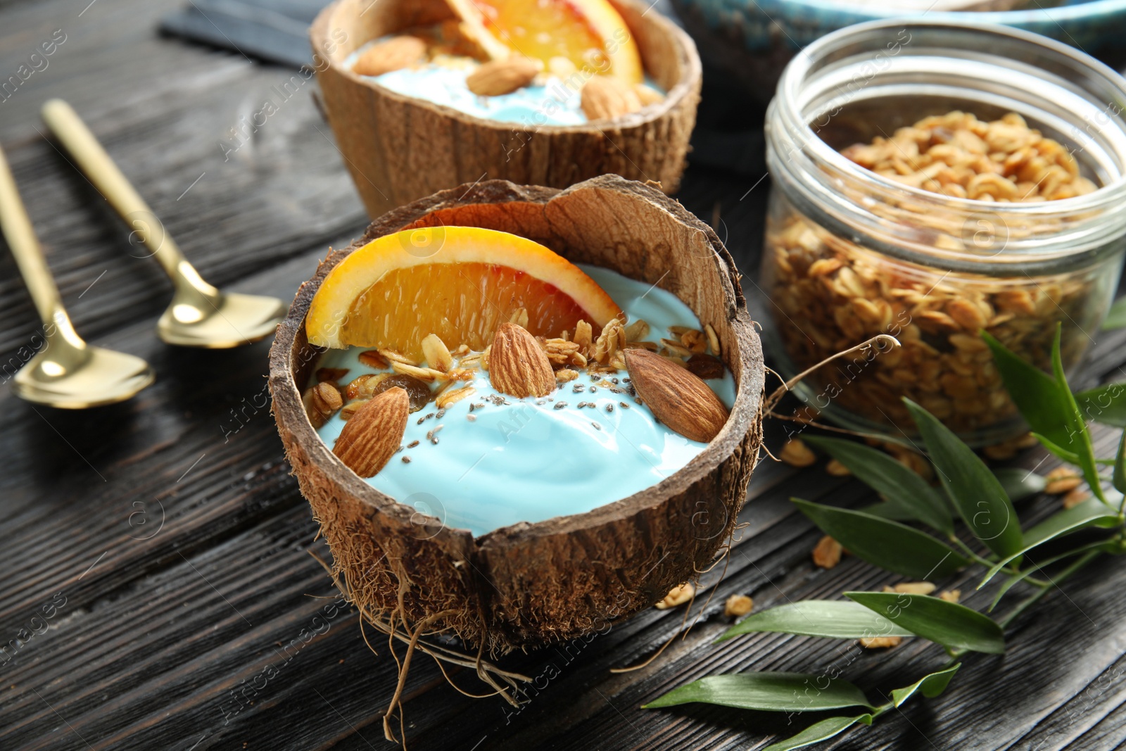 Photo of Composition with spirulina smoothie in coconut shell on wooden table