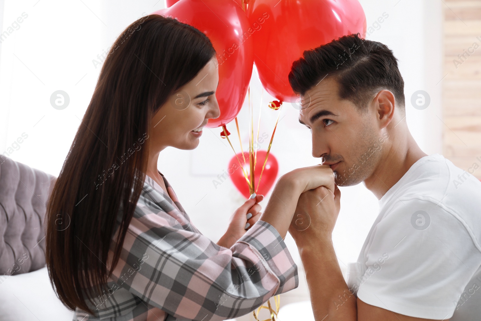 Photo of Beautiful couple with heart shaped balloons in bedroom