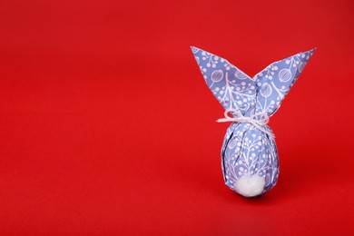 Easter bunny made of wrapping paper and egg on red background. Space for text