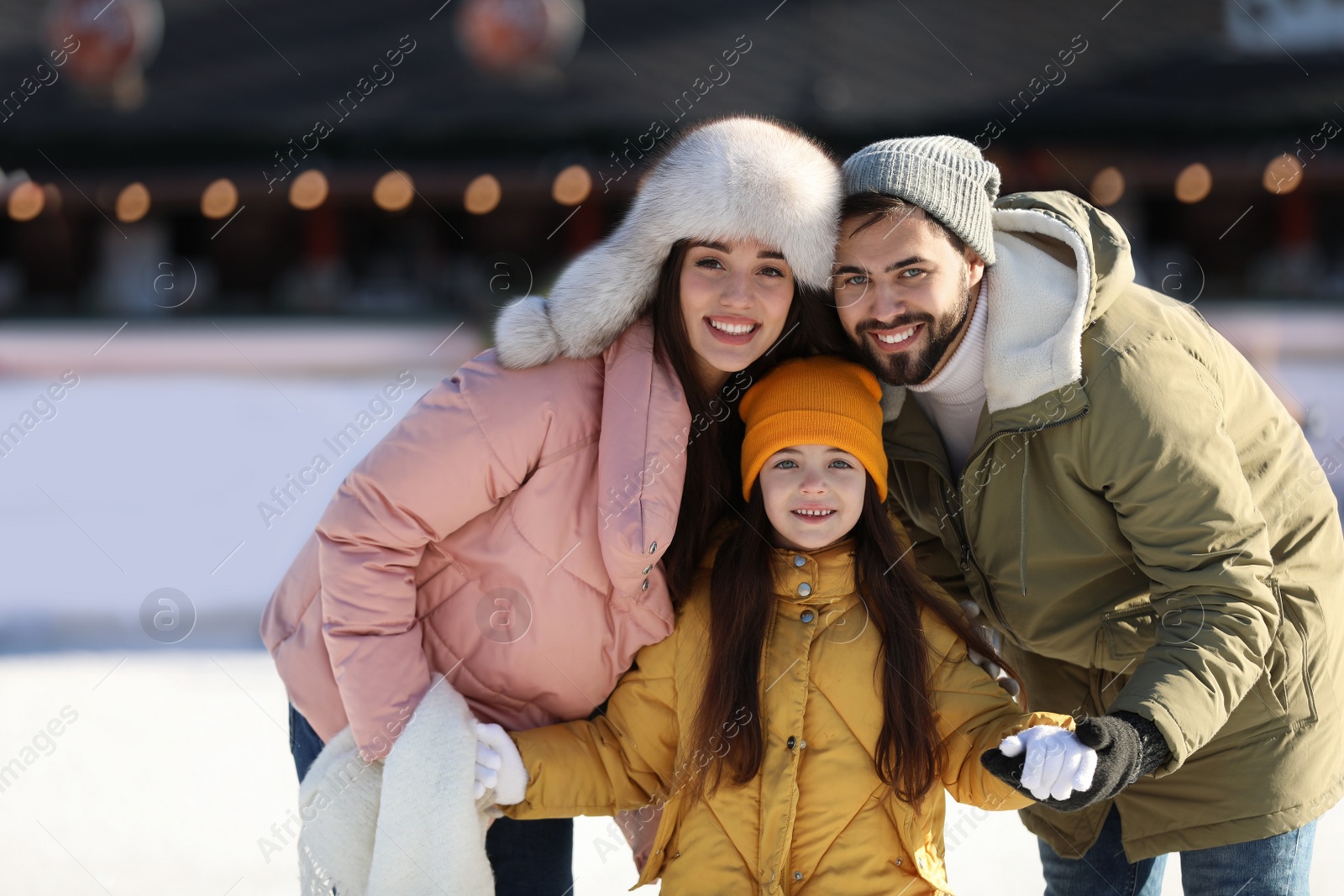 Image of Happy family spending time together at outdoor ice skating rink