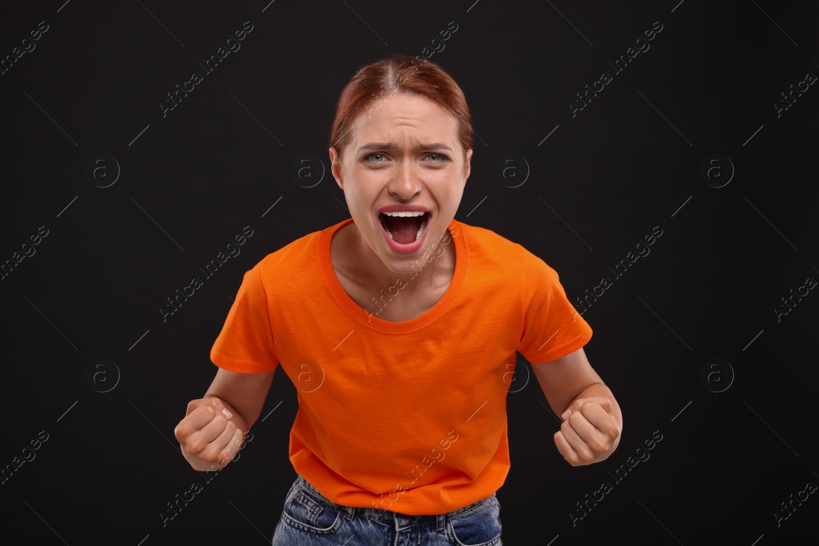 Photo of Emotional sports fan in orange t-shirt on black background