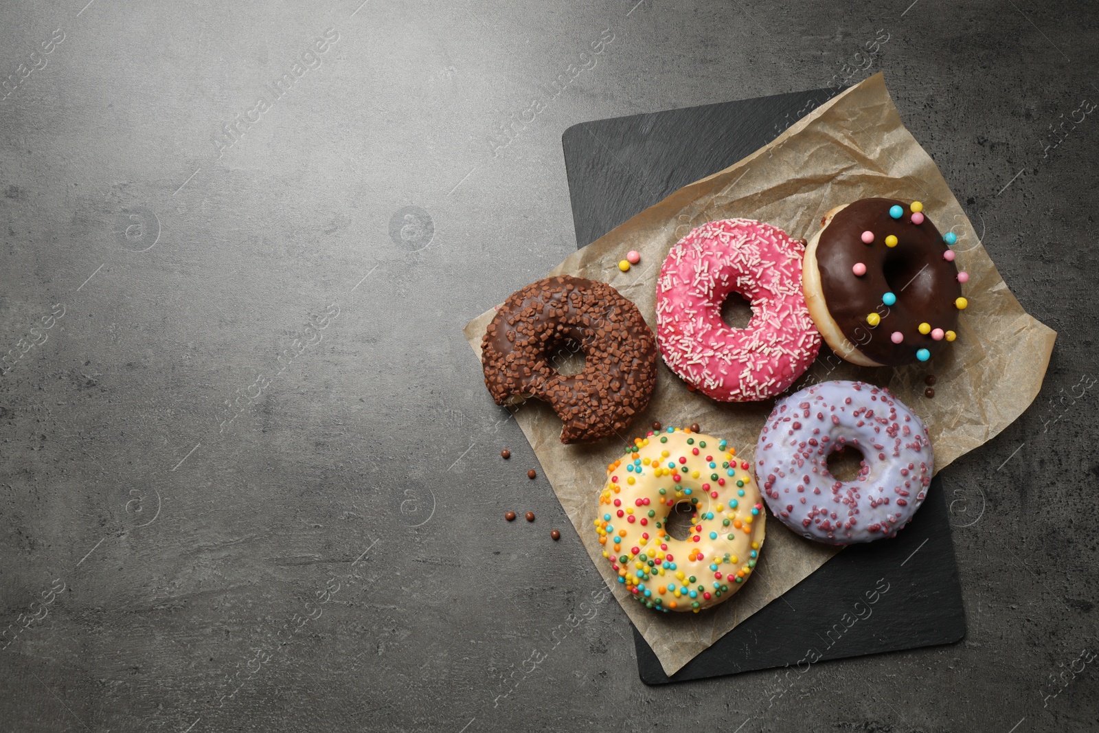 Photo of Delicious glazed donuts on grey table, top view. Space for text