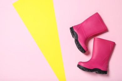 Bright pink rubber boots on color background, top view. Space for text
