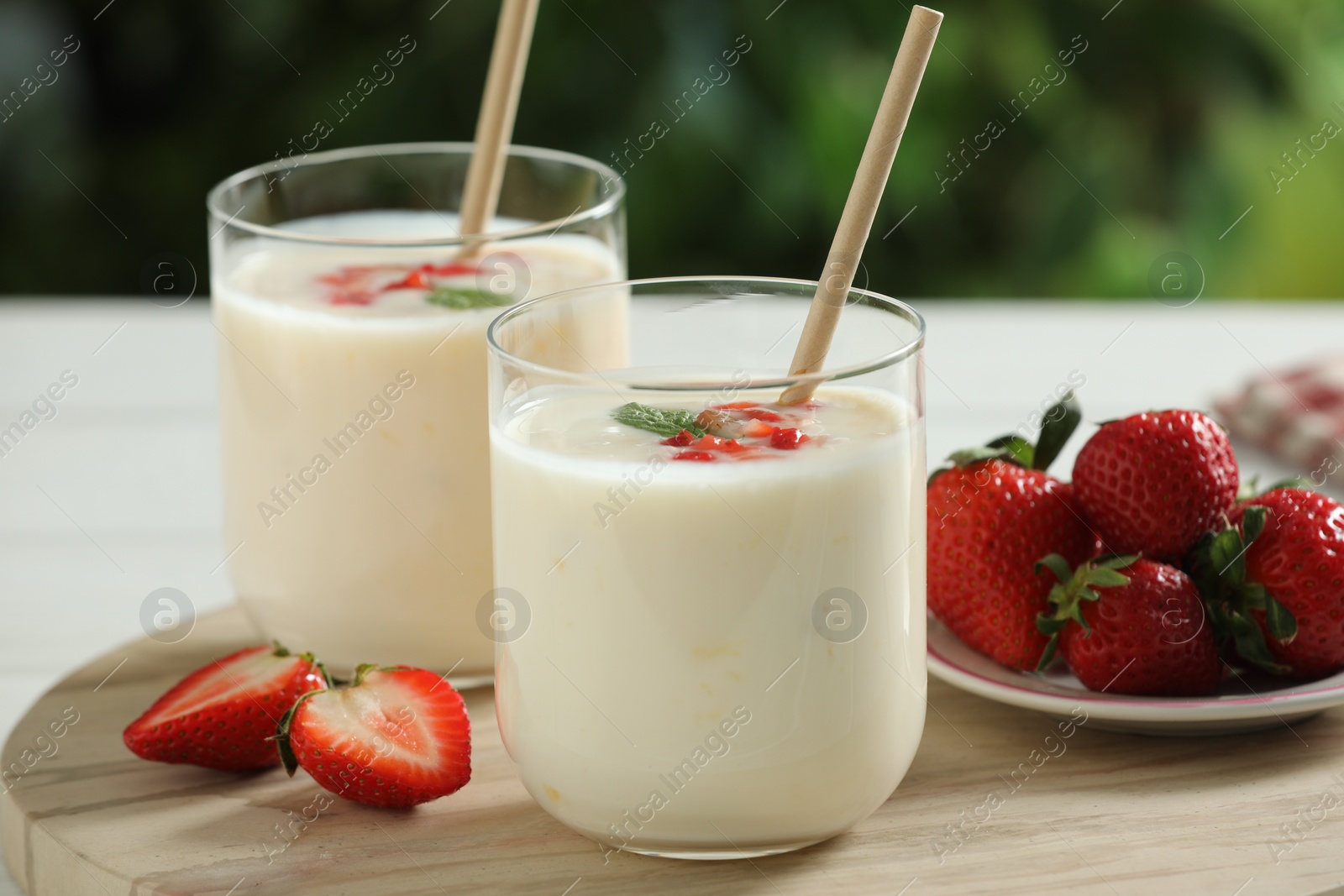 Photo of Tasty yogurt in glasses and strawberries on table outdoors, closeup