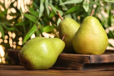 Fresh ripe pears on wooden table against blurred background