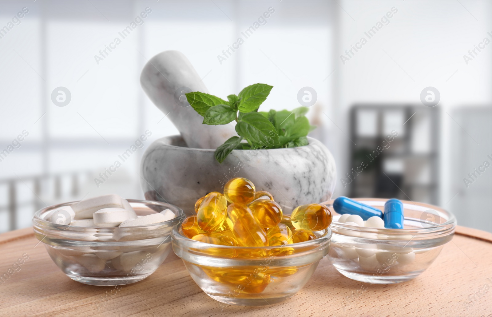 Image of Mortar with fresh mint and pills on wooden surface in medical office