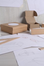 Creating packaging design. Drawings, boxes and ruler on light wooden table, closeup