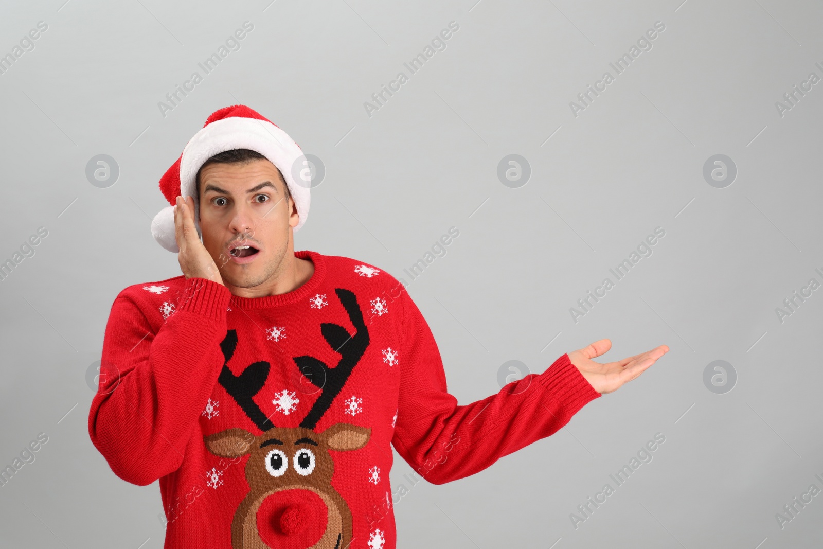 Photo of Surprised man wearing Santa hat on grey background, space for text
