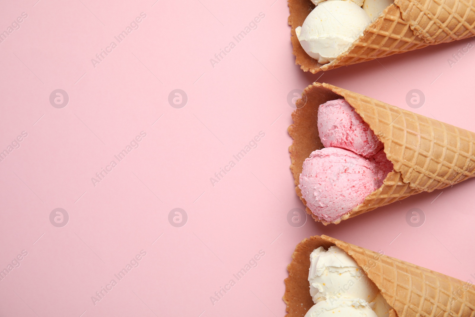 Photo of Delicious ice creams in wafer cones on pink background, flat lay. Space for text