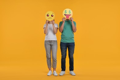 People covering faces with emoticons on yellow background