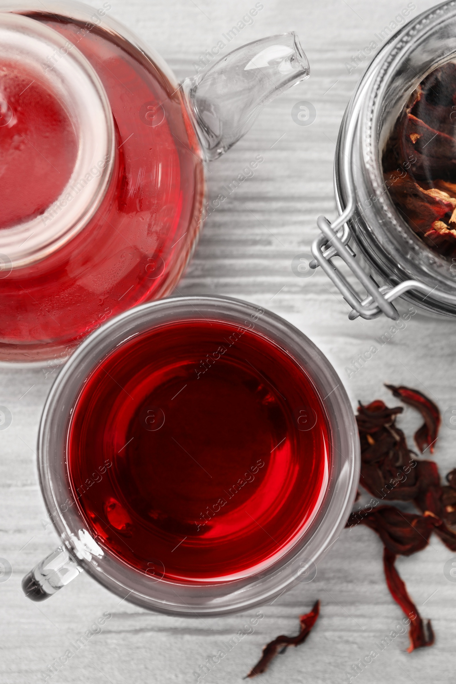 Photo of Delicious hibiscus tea and dry flowers on white wooden table, flat lay