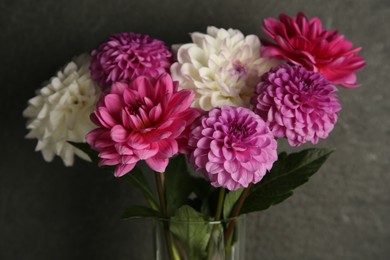 Photo of Bouquet of beautiful Dahlia flowers near dark grey wall, closeup