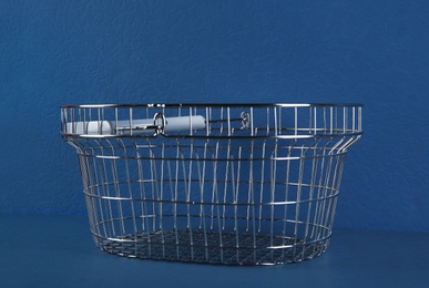 Empty metal shopping basket on blue background