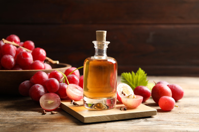 Photo of Bottle of natural grape seed oil on wooden table. Organic cosmetic