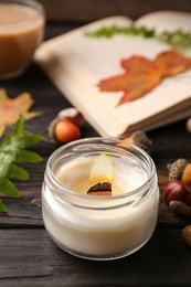 Photo of Composition with scented candle and autumn leaves on wooden table