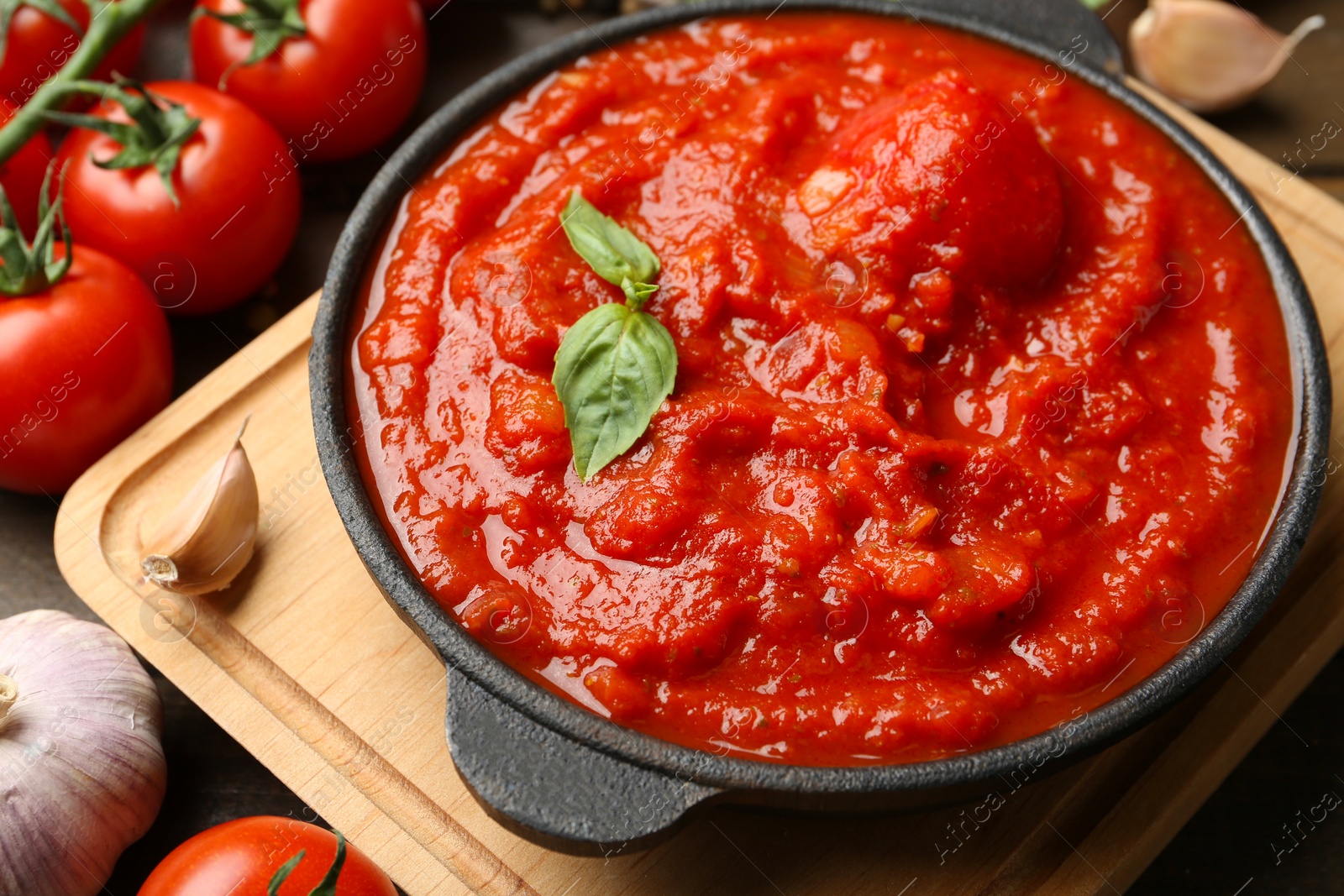 Photo of Homemade tomato sauce in bowl and ingredients on table, closeup